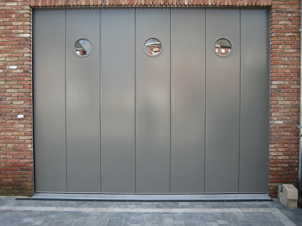 Porte de garage sectionnelle grise à refoulement latéral, avec trois hublots wizeo fermetures réalisations