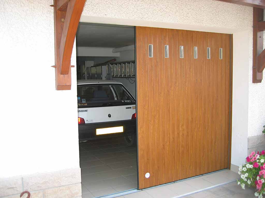 Porte de garage à lames à refoulement latéral couleur bois avec hublots rectangulaires, wizeo fermetures réalisations